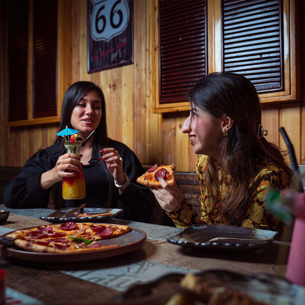Customers enjoying Italian food around a table at an Italian restaurant in Oman